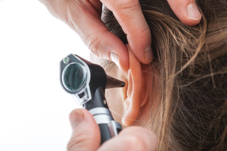 A close up of a person’s ear while a hearing specialist examines them